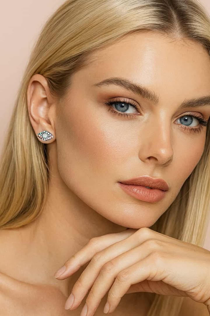 Close-up of a woman wearing a diamond earring against a beige brand name HAT_HOR Jewellerybackground