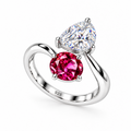 A silver 925  ring featuring a pear-cut clear gemstone and an oval deep pinkish-red gemstone, photographed on a textured white surface with a soft shadow.