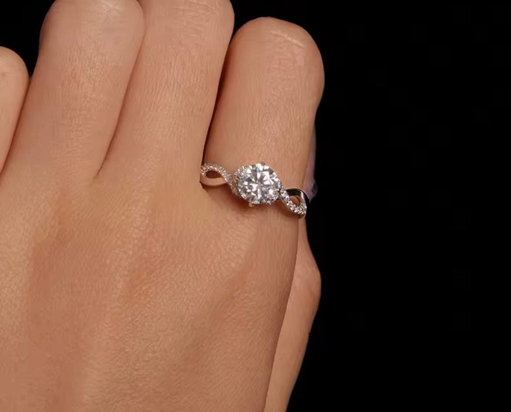 A close-up of a hand wearing a silver-925 ring with a round-cut clear moissanite stone 